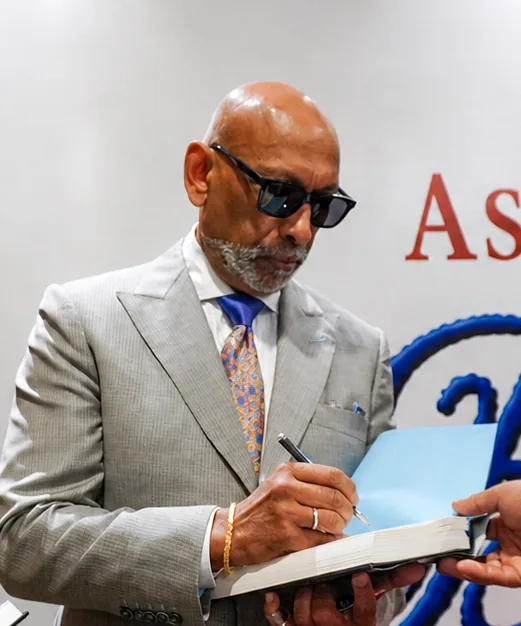 Close view of Prof. Andrew M. Ramroop signing a copy of Bespoken