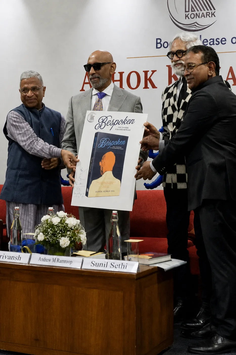Shri Harivansh, Prof. Andrew M. Ramroop and Sunil Sethi hold the Bespoken jacket on stage